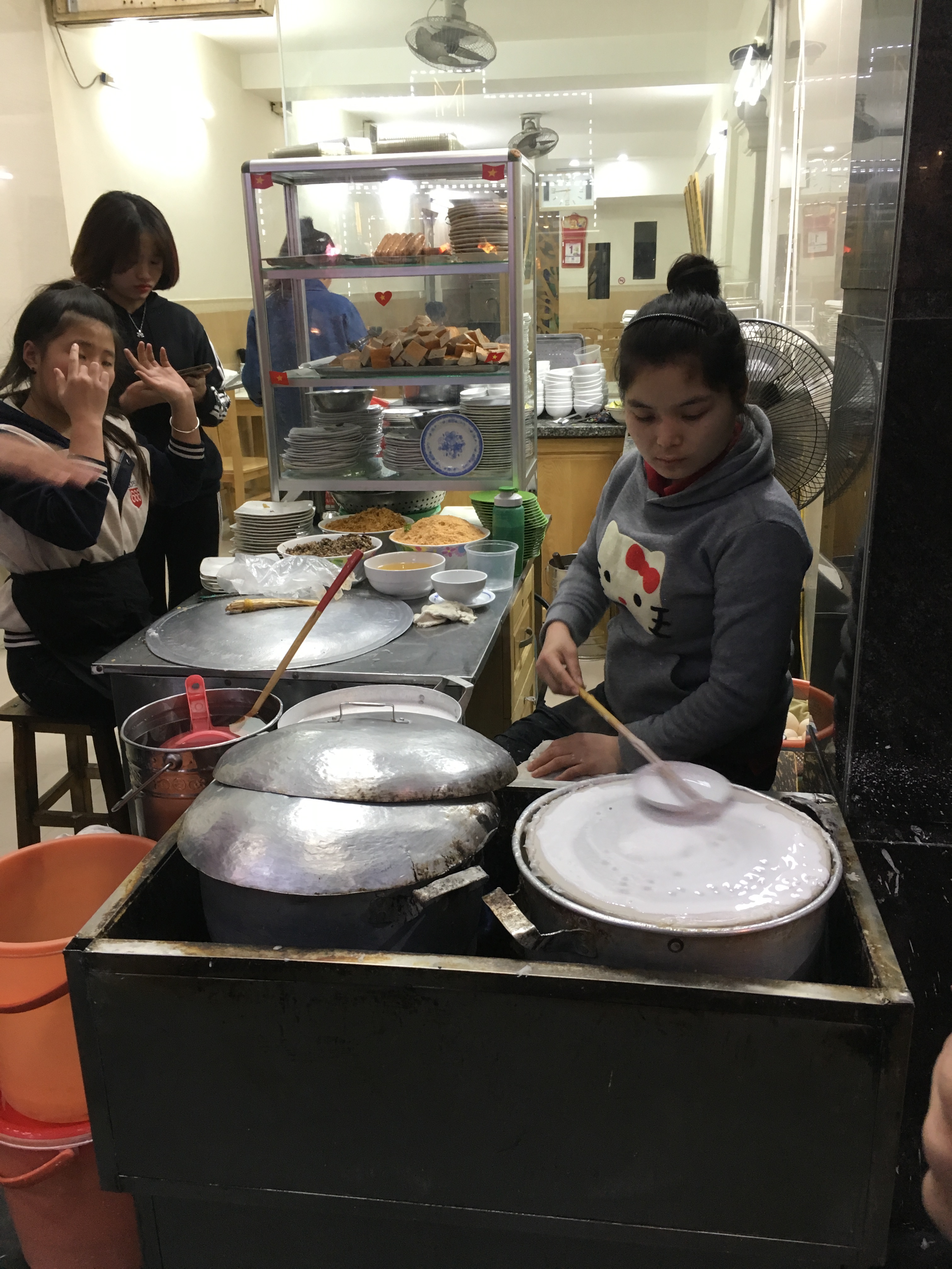 Young street vendor expertly making bhan cuon