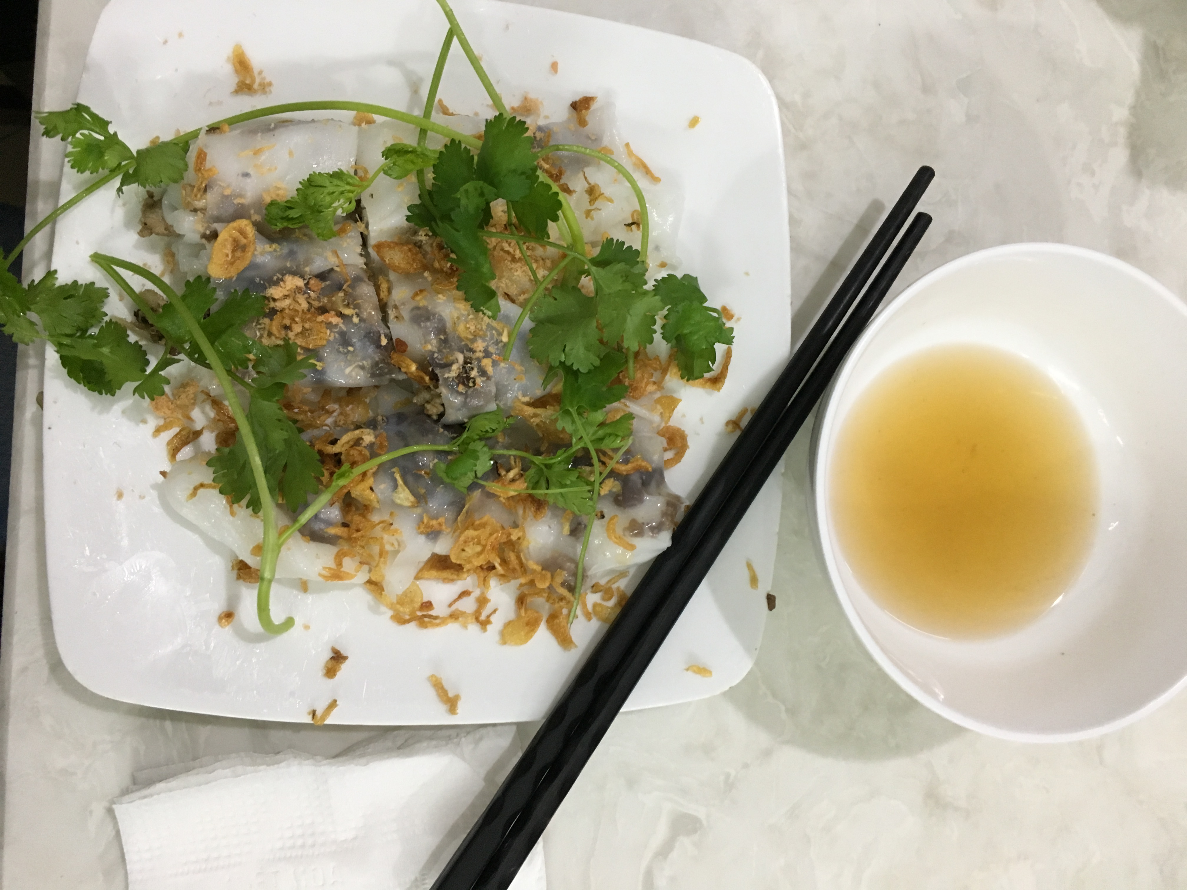 A picture of the vietnamese dish bhan cuon along with dipping sauce and chopsticks